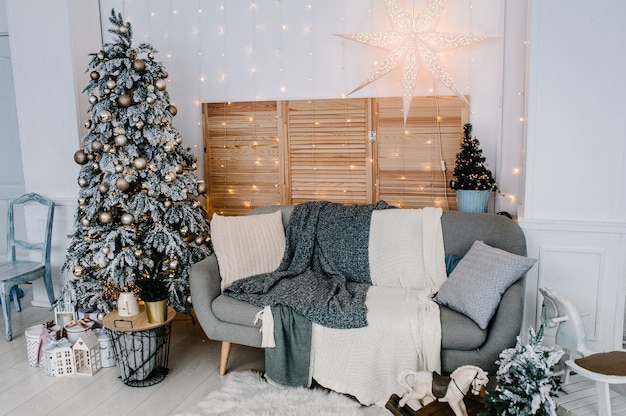 Interior decorado de Natal. Árvore de Natal com caixas de presentes em uma sala branca. Abeto decorado com guirlandas. Decoração. Feliz Natal. O conceito de férias de inverno.