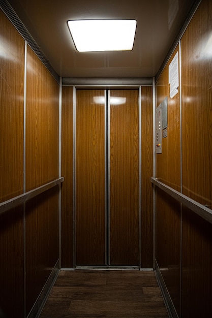 Interior dentro de una vieja cabina de ascensor soviética cerrada y limpia revestida de madera