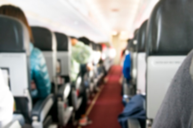 Interior do avião com foto desfocada do passageiro em assentos