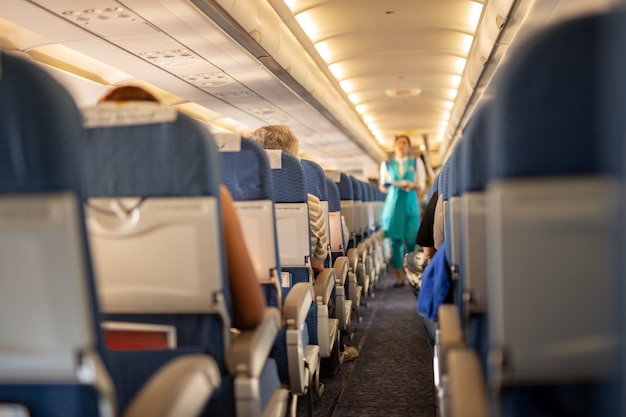 Interior do avião comercial com os passageiros em seus assentos durante o vôo.