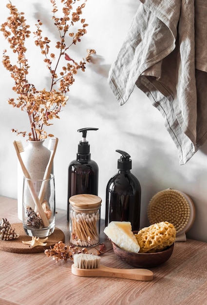 Interior do banheiro Ainda vida com flores decorativas shampoo garrafas cotonetes escovas toalhas de sabão em um fundo de madeira Minimalismo interior escandinavo