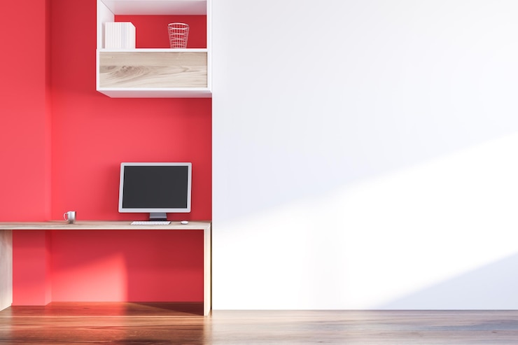 Foto interior do escritório doméstico com paredes brancas e vermelhas, piso de madeira, mesa de madeira com computador e prateleiras acima. simulação de renderização 3d