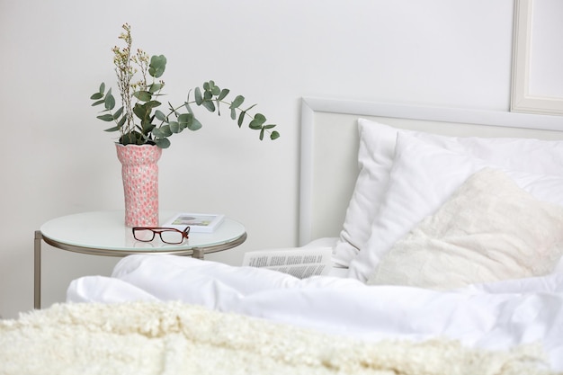 Interior do quarto com cama e flores na mesa de cabeceira