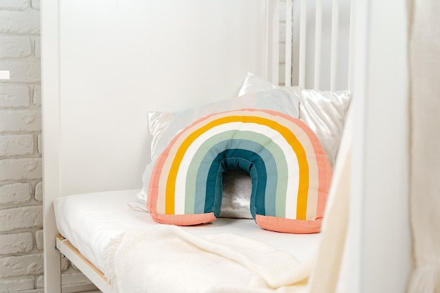 Interior do quarto das crianças com cama confortável e travesseiro arco-íris