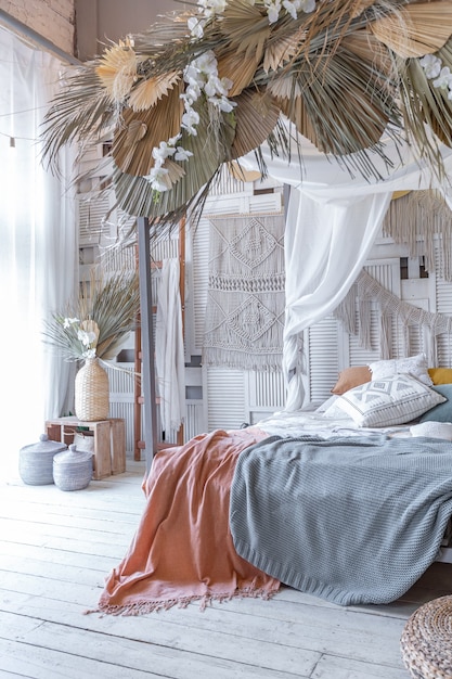 Interior de dormitorio de estilo balinés. cama con dosel con muchos textiles para la decoración y artículos de mimbre en suaves colores pastel