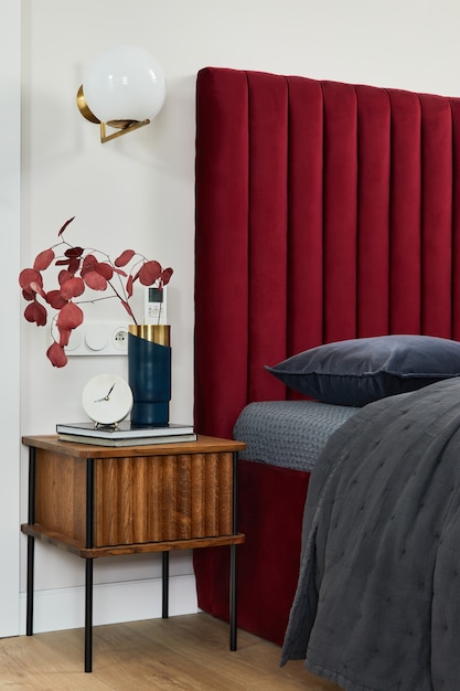 Interior de dormitorio minimalista con cama roja, ropa de cama gris y muebles de madera. Inspiración de estilo glamour. Plantilla.