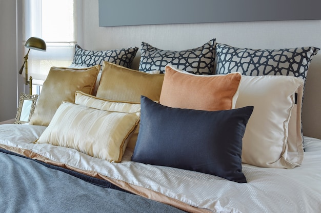 Interior de dormitorio moderno con almohadas naranjas y doradas en la cama y