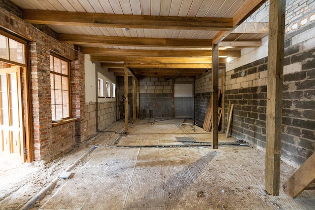 Interior de un edificio abandonado en mal estado con tuberías expuestas a escombros y puertas faltantes a la espera de renovación