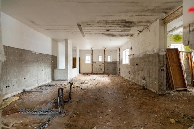 Interior de un edificio abandonado en mal estado con tuberías expuestas a escombros y puertas faltantes a la espera de renovación