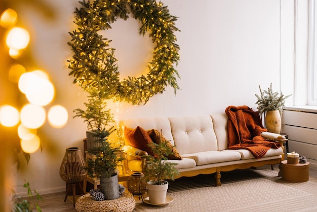 Foto interior elegante da sala de estar com pequenas árvores de abeto e decorações de natal perto do sofá