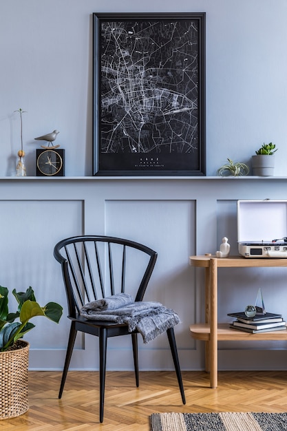 Interior de la elegante sala de estar escandinava con silla negra de diseño, consola de madera, plantas, libros, decoración, mapa del cartel