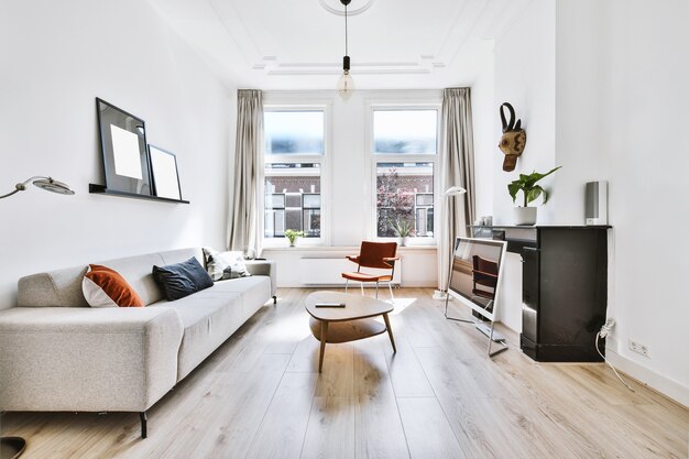 Interior de la elegante sala de estar luminosa con muebles modernos y ventanas en el apartamento