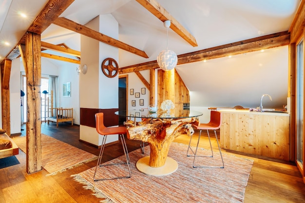 Interior em design contemporâneo de sala de estar com mesa de vidro e cozinha em apartamento moderno. Móveis para casa. Decoração. Parede e piso de madeira. Estilo de vida elegante. Estilo rústico e vintage.