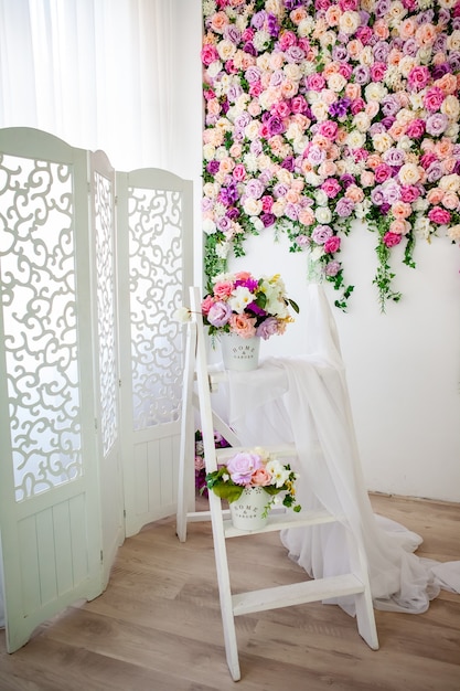 Foto interior em estilo provençal com tela branca, parede floral brilhante, balde com flores artificiais