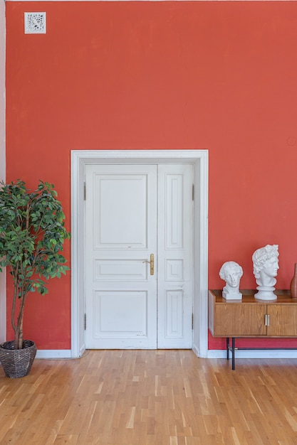 Interior de época antigua en la sala de estar de estilo del siglo XIX con paredes de color rojo brillante, piso de madera y luz solar directa dentro de la habitación.