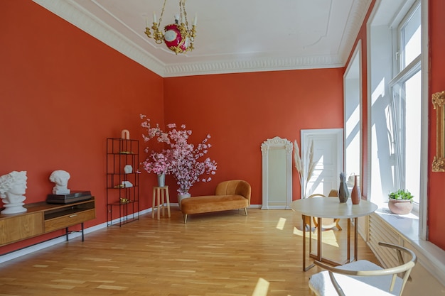 Interior de época antigua en la sala de estar de estilo del siglo XIX con paredes de color rojo brillante, piso de madera y luz solar directa dentro de la habitación.