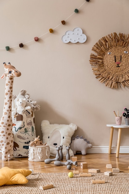 Interior escandinavo elegante de quarto infantil com brinquedos naturais, decoração suspensa, móveis de design, animais de pelúcia, ursinhos de pelúcia e acessórios. Paredes bege. Design de interiores da sala de criança. Modelo.