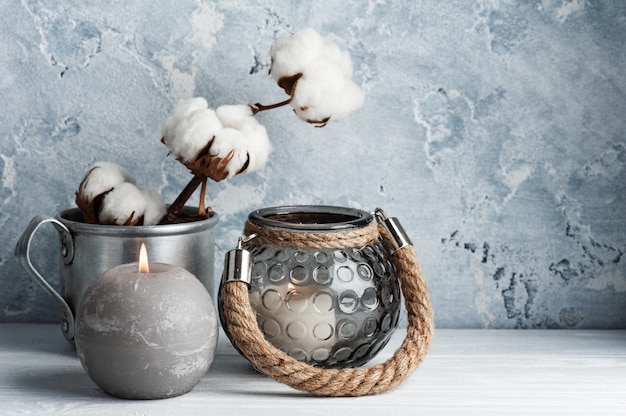 Interior escandinavo con flores de algodón y velas encendidas en un arreglo minimalista.