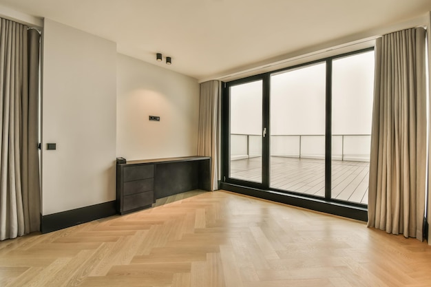 El interior de una espaciosa habitación vacía con una ventana panorámica y acceso al balcón