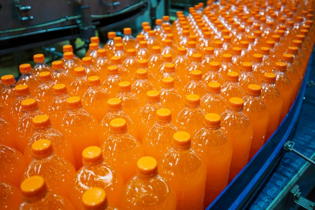 Interior de la fábrica de bebidas. Transportador que fluye con botellas para jugo o agua.