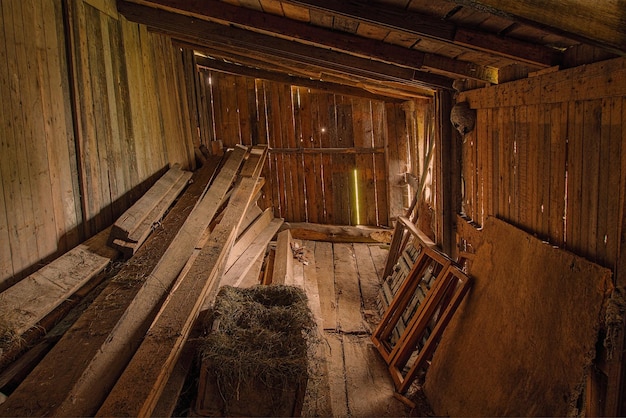 Interior de granero de madera oscura con montones de tablas y marcos de madera