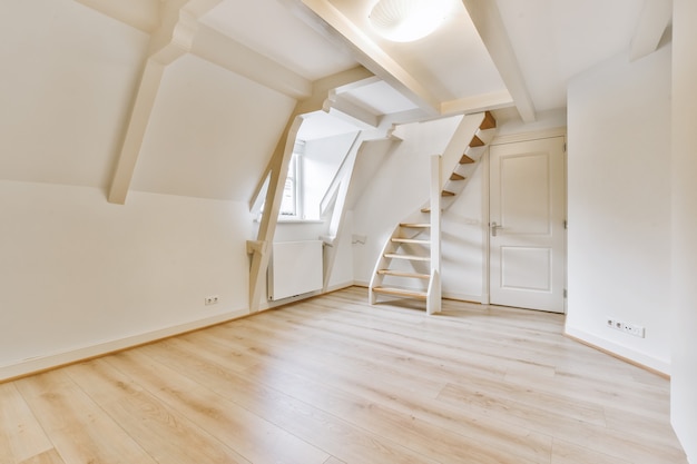 Interior de habitación grande con pequeña ventana y escalera