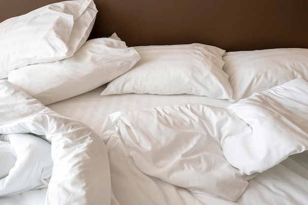 Interior de la habitación del hotel por la mañana con cama desordenada Ropa de cama blanca arrugada