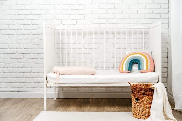 Interior de la habitación de los niños con cama cómoda y almohada de arco iris