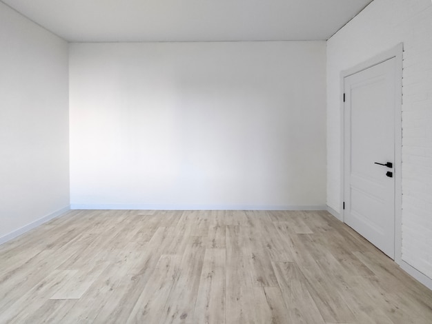 Interior de la habitación vacía - pared blanca con puerta y piso de madera
