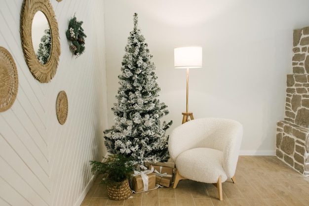 El interior de una hermosa casa de luz decorada para el Nuevo árbol de Navidad un sillón blanco una lámpara de pie