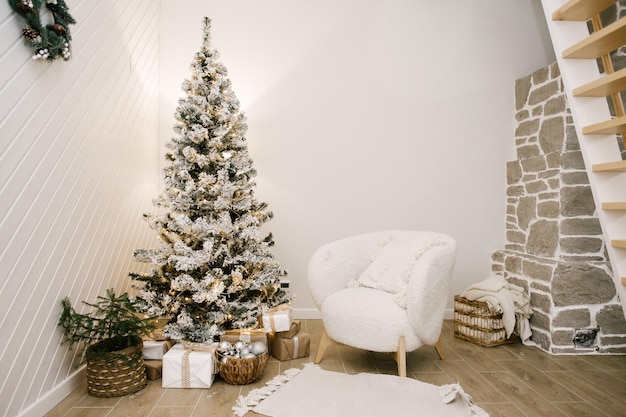 El interior de un hermoso faro decorado al Nuevo árbol de Navidad un sillón blanco una chimenea y una escalera