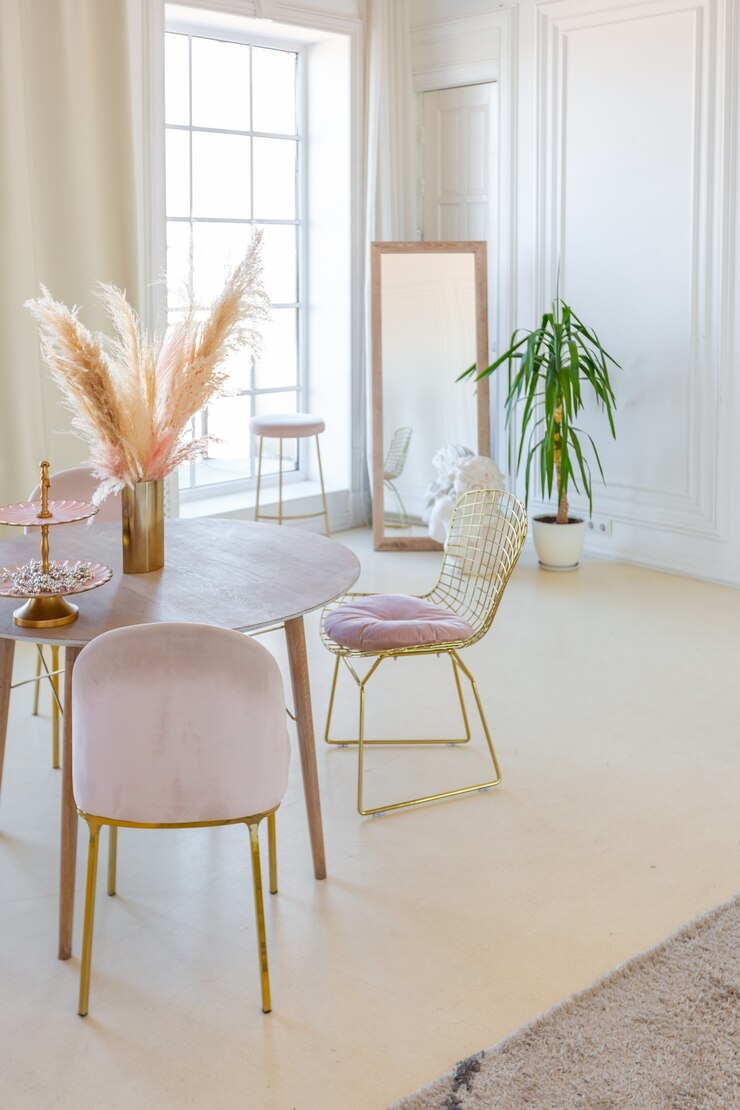Interior ligero delicado y acogedor de la sala de estar con muebles elegantes y modernos de color rosa pastel y paredes blancas con molduras de estuco a la luz del día