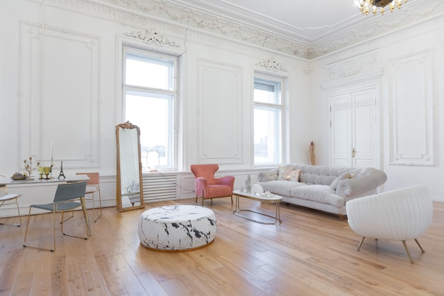 Interior de lujo de estilo barroco muy ligero de gran salón. Paredes blancas decoradas con estuco impresionante. Apartamento de estilo real con muebles elegantes con elementos dorados.