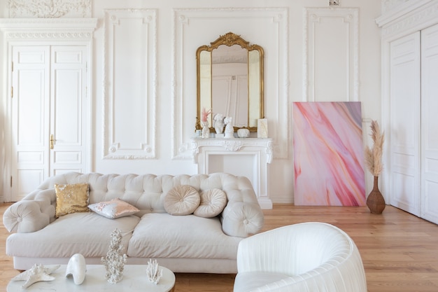 Interior de lujo de estilo barroco muy ligero de gran salón. Paredes blancas decoradas con estuco impresionante. Apartamento de estilo real con muebles elegantes con elementos dorados.