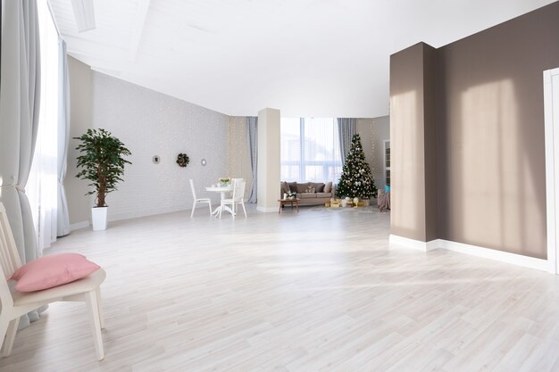 Interior de lujoso apartamento caro en colores claros. diseño minimalista contemporáneo con estilo. lleno de luz solar. mucho espacio decorado con árbol de navidad.