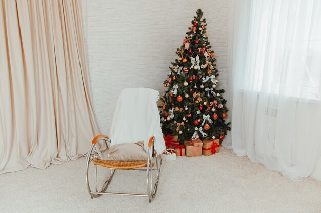 Interior luminoso de Año Nuevo con un árbol de Navidad y una mecedora.