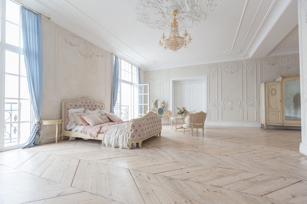 Interior luminoso de lujo en estilo barroco. Una habitación espaciosa con un hermoso mobiliario de carretera elegante, una chimenea y flores. Planta de estuco en las paredes y parquet de madera clara.