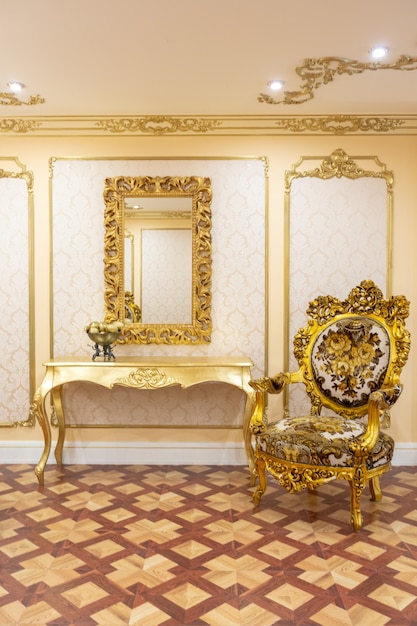 Interior luxuoso da sala de estar com belos móveis antigos esculpidos na cor dourada e decorações nas paredes no estilo do palácio real