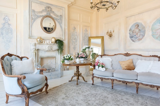 Foto interior luxuoso da sala de estar em bege pastel com mobília antiga e cara em estilo barroco. paredes decoradas com estuque e afrescos