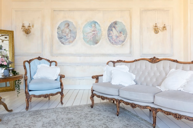 Foto interior luxuoso da sala de estar em bege pastel com mobília antiga e cara em estilo barroco. paredes decoradas com estuque e afrescos