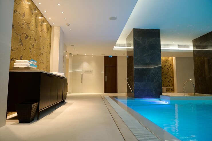 Foto interior luxuoso do spa e centro de bem-estar com piscina termal com iluminação subaquática e cascata.
