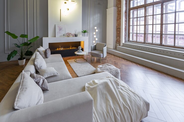Interior minimalista de un apartamento ultramoderno de planta abierta con paredes blancas y grises con un relieve y muebles tapizados con estilo gris y grandes ventanales