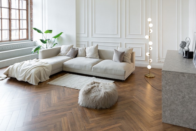 Interior minimalista de um apartamento ultramoderno de plano aberto com paredes brancas e cinza com um relevo e móveis estofados elegantes em cinza e janelas enormes