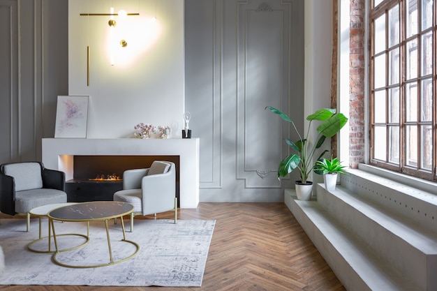 Interior minimalista de um apartamento ultramoderno de plano aberto com paredes brancas e cinza com um relevo e móveis estofados elegantes em cinza e janelas enormes
