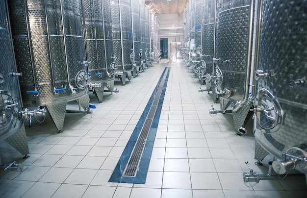 Interior moderno de bodega, grandes cubas de fermentación brillantes en perspectiva, enfoque selectivo