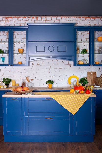 Interior moderno cozinha azul em estilo loft com móveis. Cozinha escandinava elegante em decoração. cozinha de madeira em estilo rústico. Mesa de madeira vazia e decoração amarela primavera no interior da cozinha.