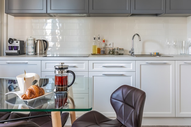 Interior moderno da cozinha bem iluminada do apartamento com mesa para refeições e eletrodomésticos embutidos