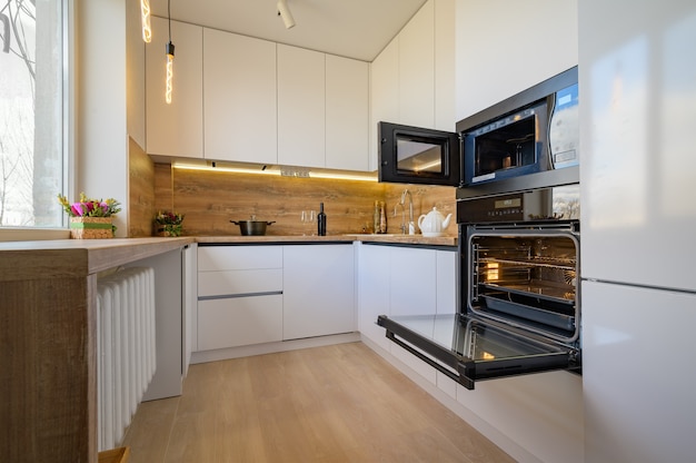 Interior moderno da cozinha de madeira branca e bege com forno aberto