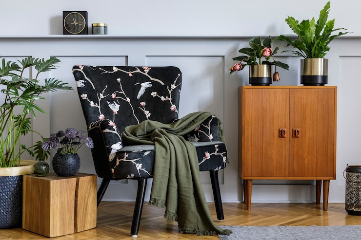 Foto interior moderno da sala de estar com poltrona de design, cômoda vintage de madeira, painéis de madeira com prateleira, muitas plantas, mesa de centro, parede cinza e acessórios personalizados na decoração da casa.