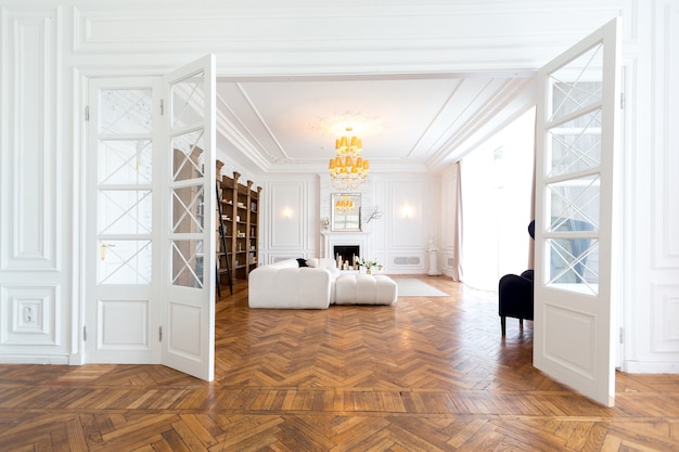 Interior moderno de um luxuoso apartamento amplo e luminoso de dois quartos. paredes brancas, móveis luxuosos e caros, piso de parquete e portas internas brancas